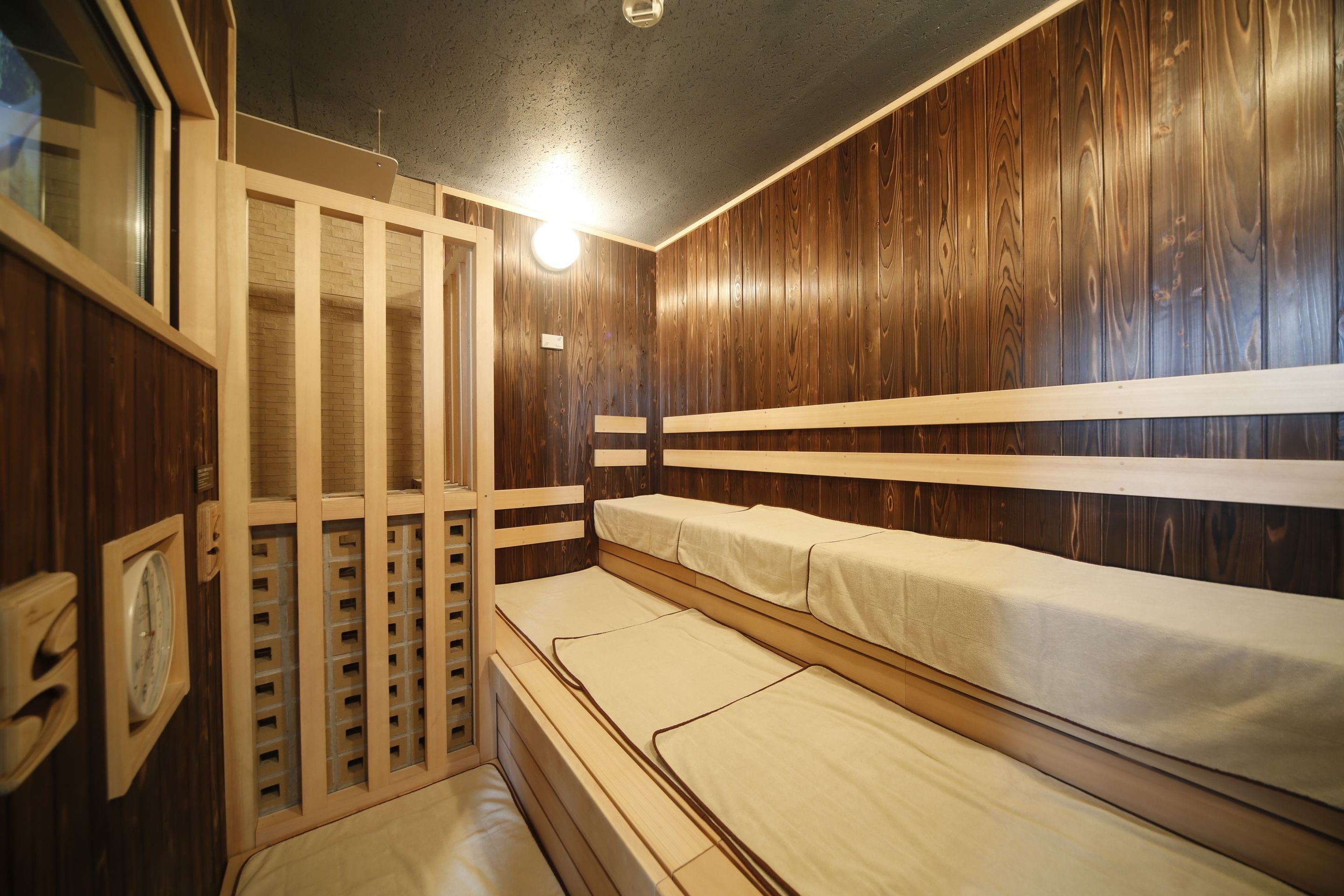 Una habitación con paredes de paneles de madera, una litera con colchón y una pequeña ventana.