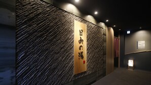 A hallway with a textured wall and a wooden sign with Japanese characters. - Hotel Dormy Inn Miyazaki Natural Hot Spring (Miyazaki)