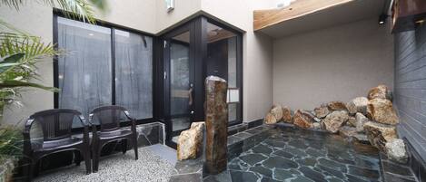 A spa area with a stone pool, two wooden benches, and a door leading to a room.