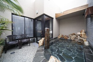 A spa area with a stone pool, two wooden benches, and a door leading to a room.