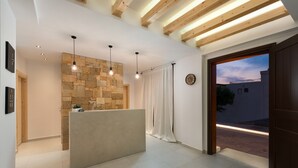 Zona de recepción con pared de piedra, un mostrador de recepción, lámparas colgantes y vista a la calle.