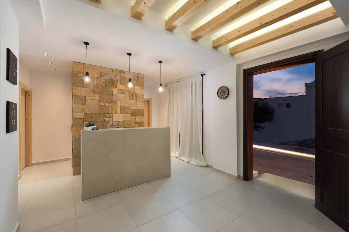 A reception area with a stone wall, a reception desk, pendant lights, and a view of the street outside.