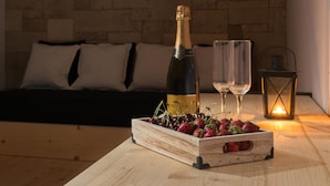 Una mesa de madera con una botella de champán, dos copas y un cesto de madera lleno de fresas.