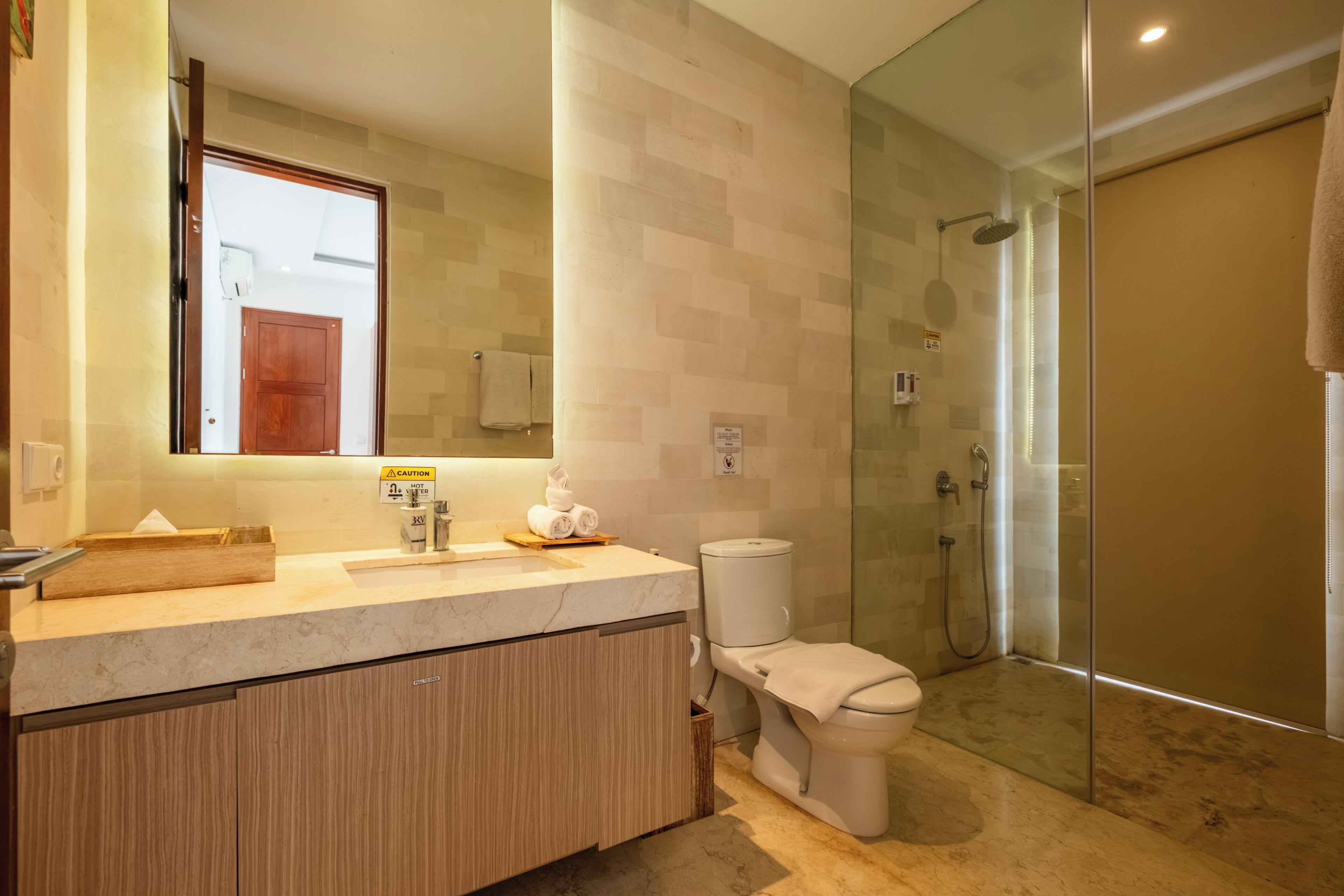 Une salle de bain moderne avec une douche à parois de verre, un meuble-lavabo en bois et des toilettes.