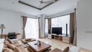A modern living room with a sofa set, a coffee table, a TV, and a dining area with a table and chairs. - Bali Residence Villa (Ungasan)