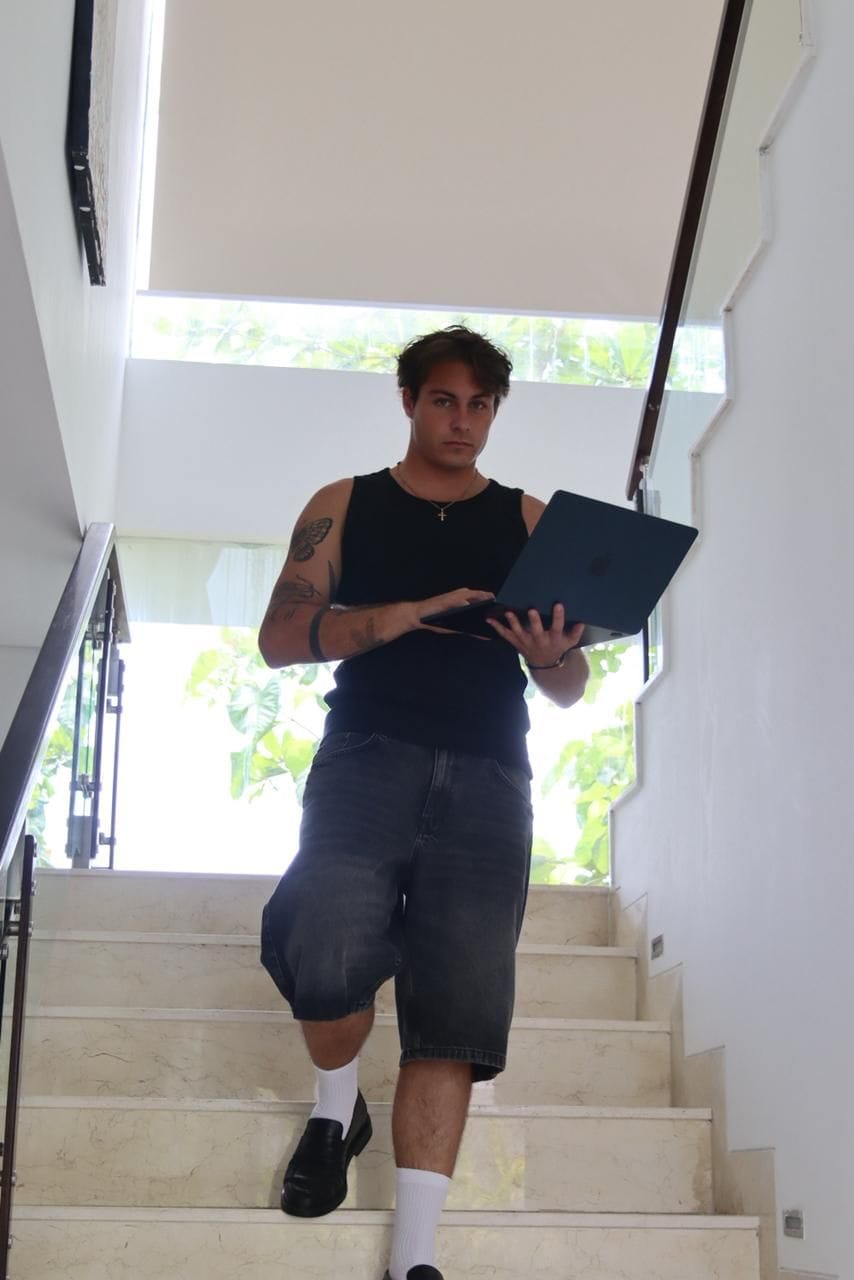 A person descending a staircase indoors, holding a laptop.