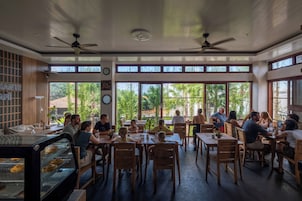 Un restaurante con mobiliario de madera, ventanas amplias y ventiladores de techo.