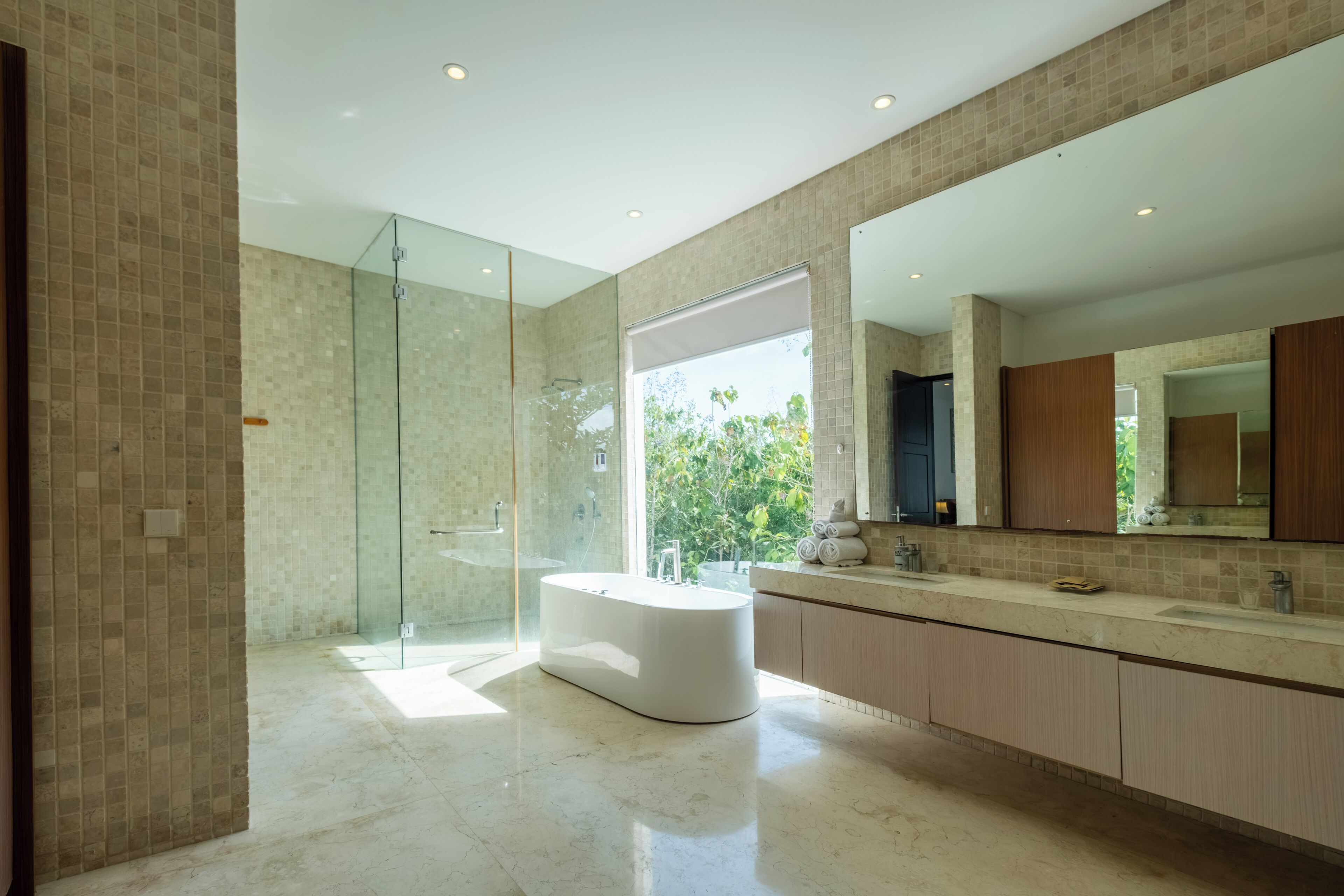 Un baño moderno con ducha envuelta en vidrio, una bañera independiente y un tocador amplio con espejo.