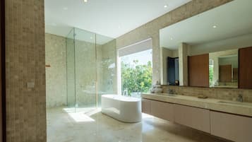 A modern bathroom with a glass-enclosed shower, a freestanding bathtub, and a large vanity with a mirror.