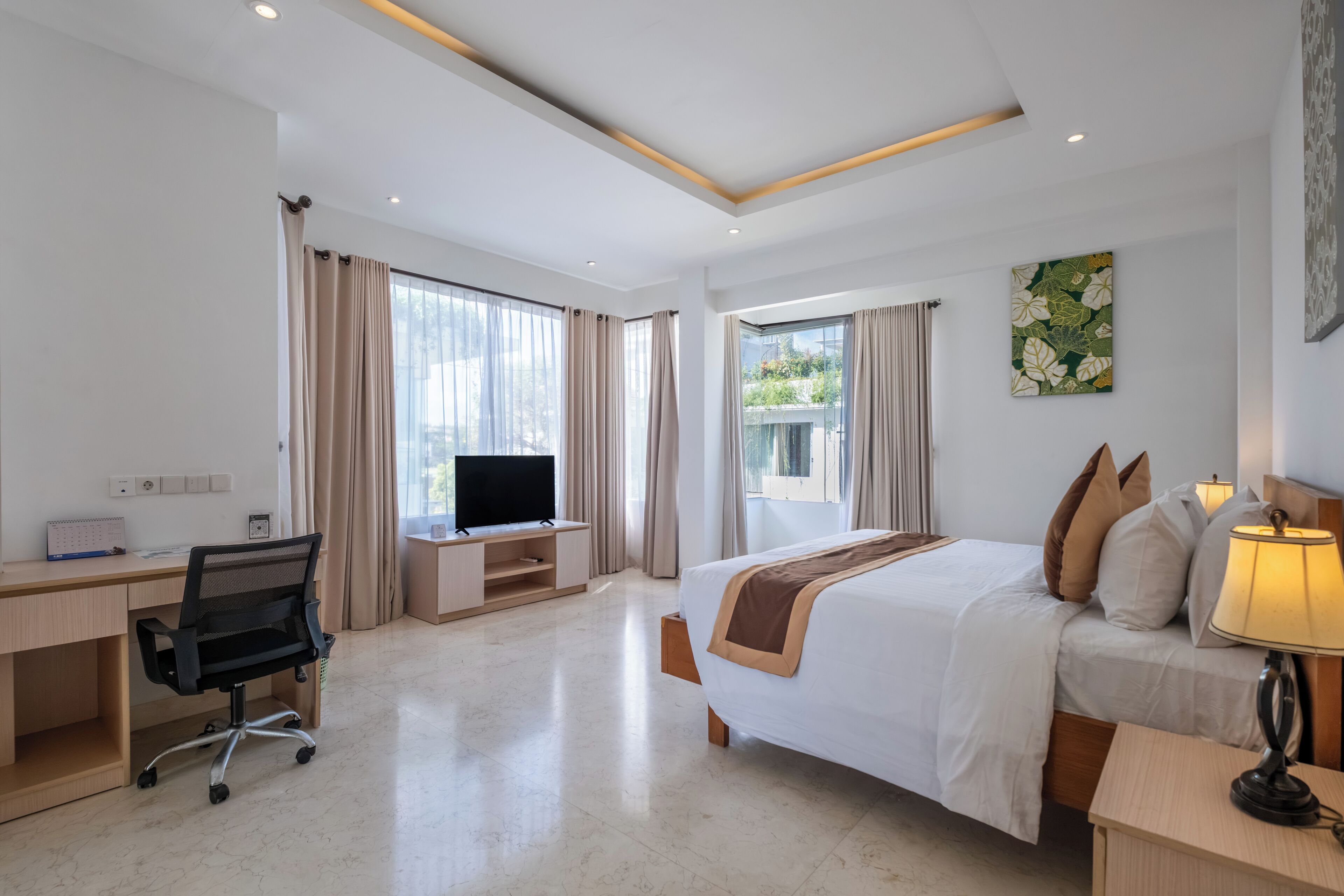 A hotel room with a bed, desk, chair, television, and a window with curtains.