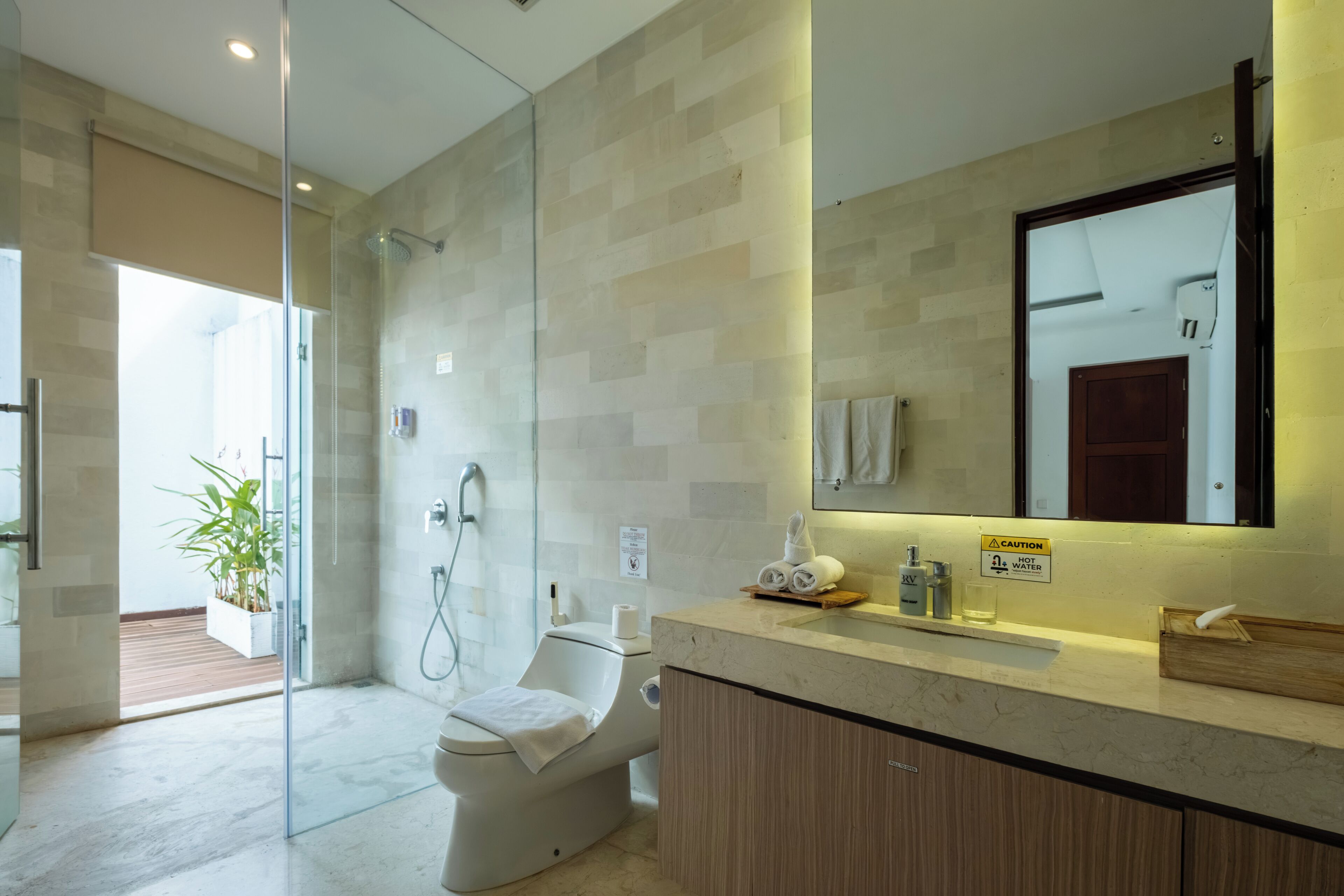 Une salle de bain moderne avec une douche à parois de verre, des toilettes, un meuble-lavabo avec un miroir et un évier.