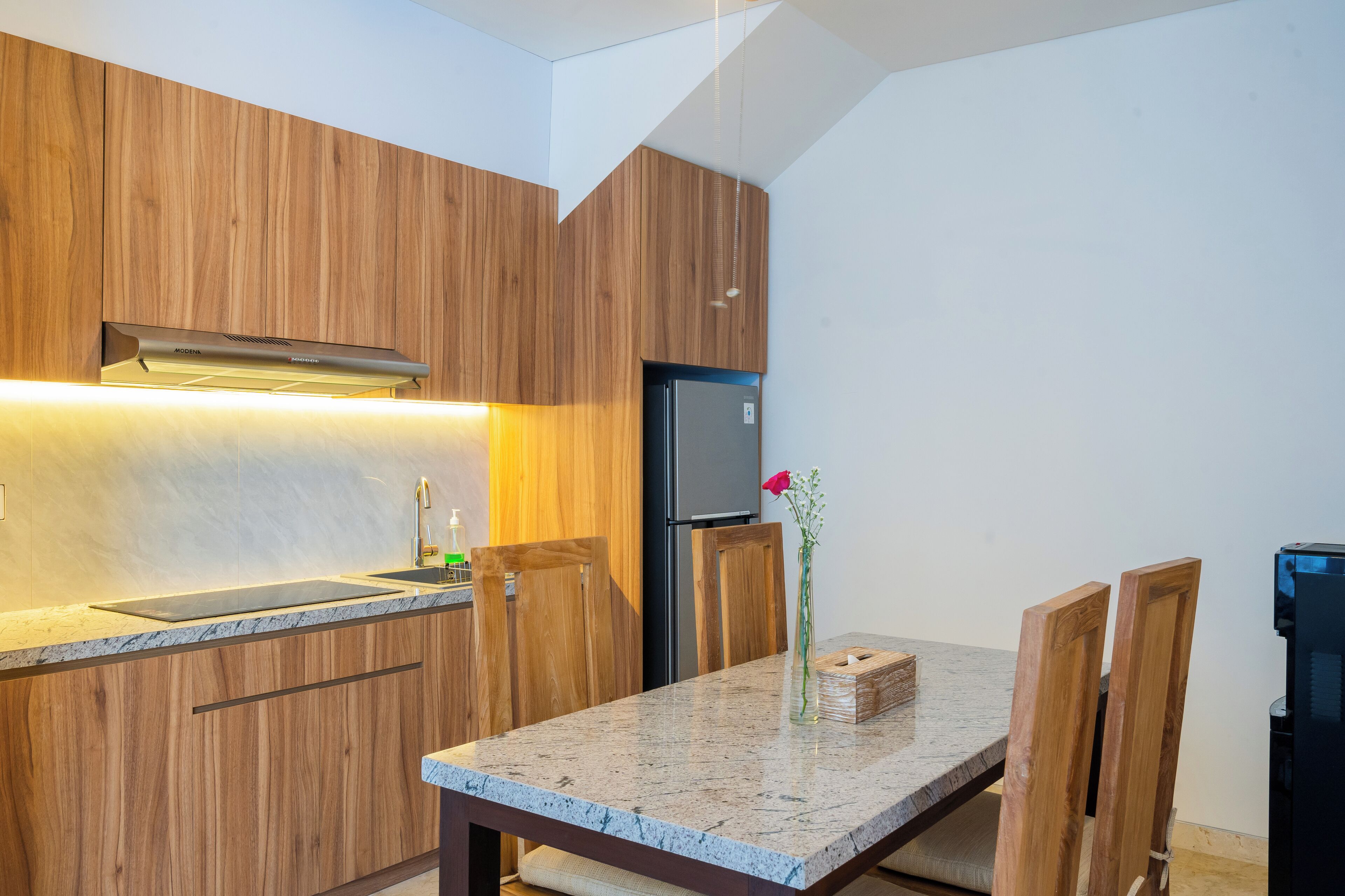 Une cuisine moderne avec des meubles en bois, un plan de travail en granit, une cuisinière encastrée et un réfrigérateur.