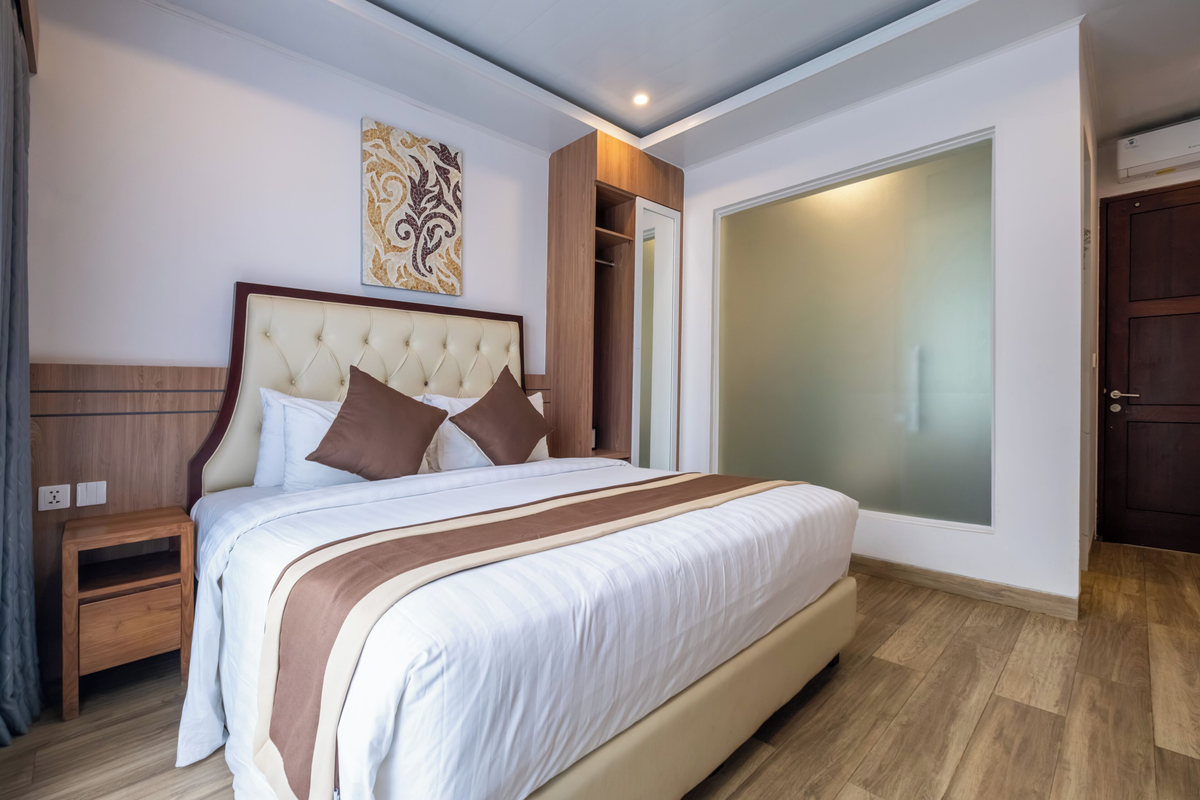 Ein Schlafzimmer mit einem großen Bett, einem Nachttisch, einem Kleiderschrank und einem an der Wand hängenden Kunstwerk.