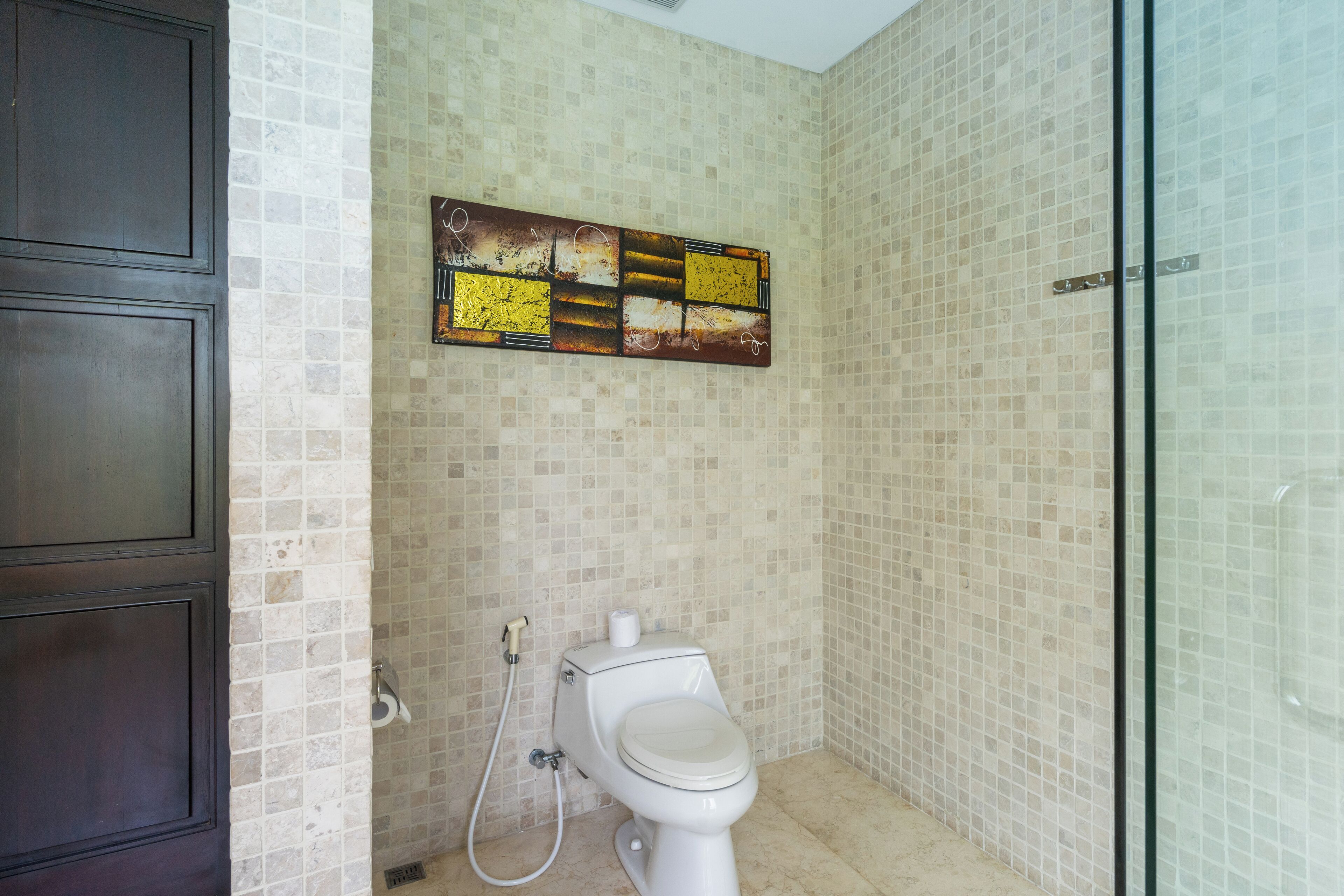 A bathroom with a toilet, a shower, and a glass door.
