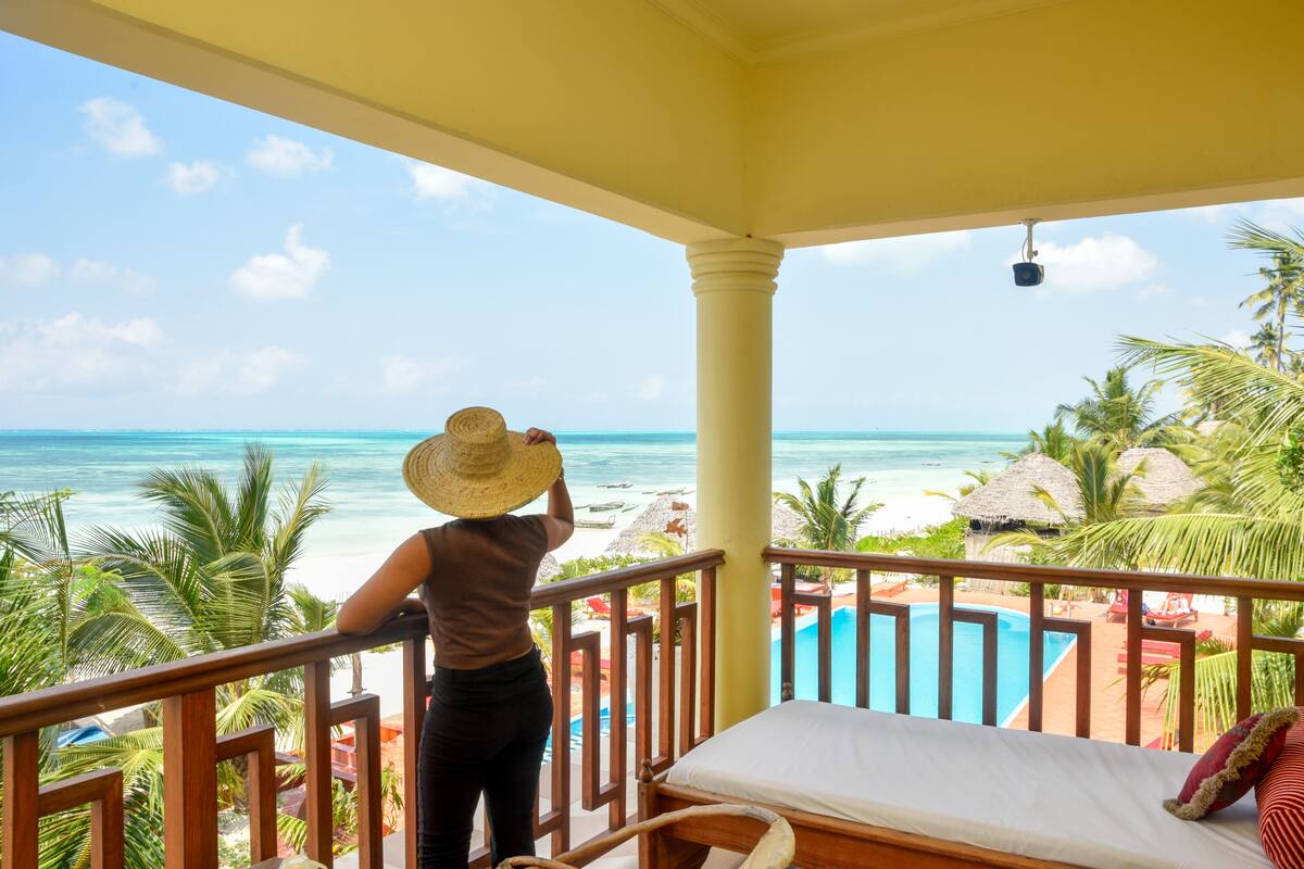 Un balcó amb vista a l'oceà, una piscina i vegetació tropical.