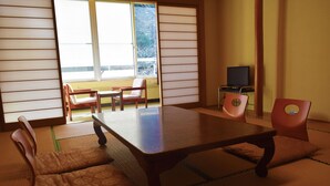 Een traditionele Japanse kamer met tatami vloerbedekking, een lage tafel en twee houten stoelen.