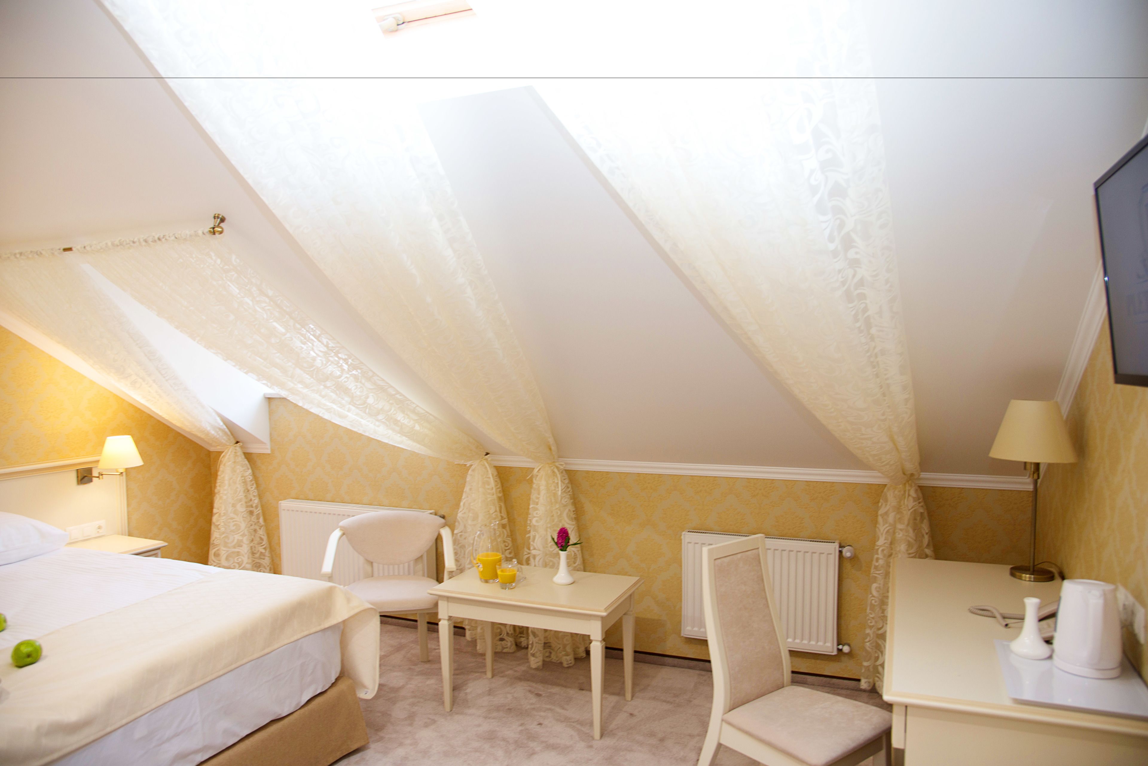 Una camera d'albergo con un letto, una scrivania, una sedia e un tavolo con un vaso e due bicchieri.