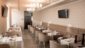 Un ristorante con diversi tavoli apparecchiati, un lampadario e un televisore a parete.