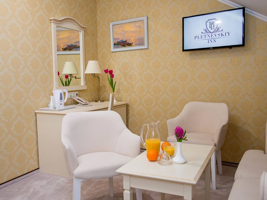 A hotel room with a bed, a desk with a lamp, a TV, and a vase with flowers.
