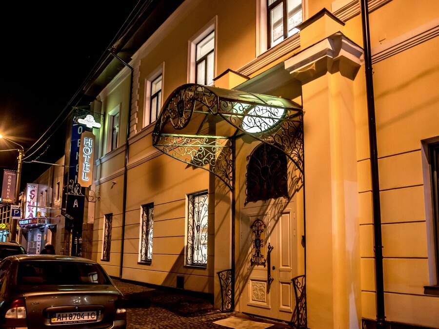 Entrada de hotel com escadaria em ferro forjado e placa indicando ser um hotel.
