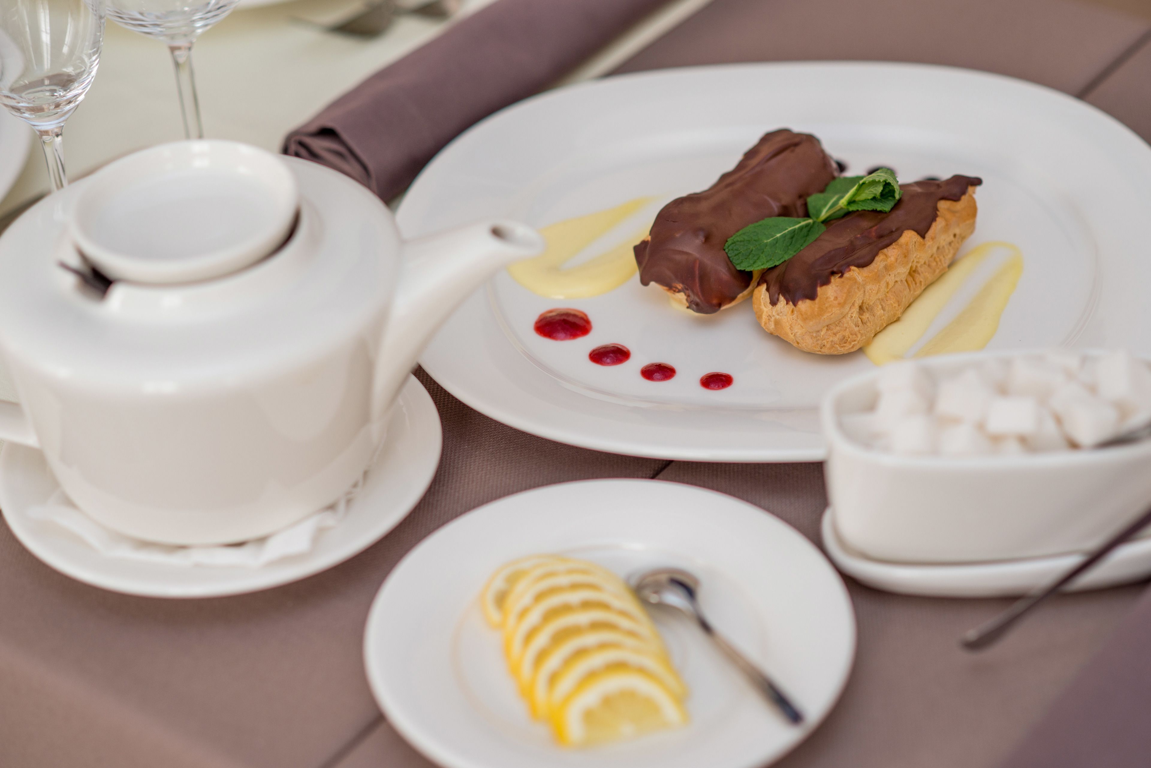 Un plato de postre con chocolate y crema, una rodaja de limón y un cuenco pequeño de cubitos de azúcar.