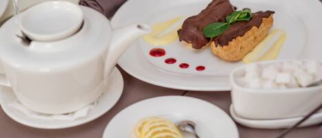 Un plato de postre con chocolate y crema, una rodaja de limón y un cuenco pequeño de cubitos de azúcar.