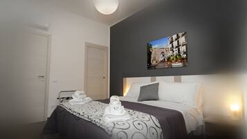A hotel room with a neatly made bed, a headboard with a picture of a cityscape, a bedside table with a lamp, and a door.