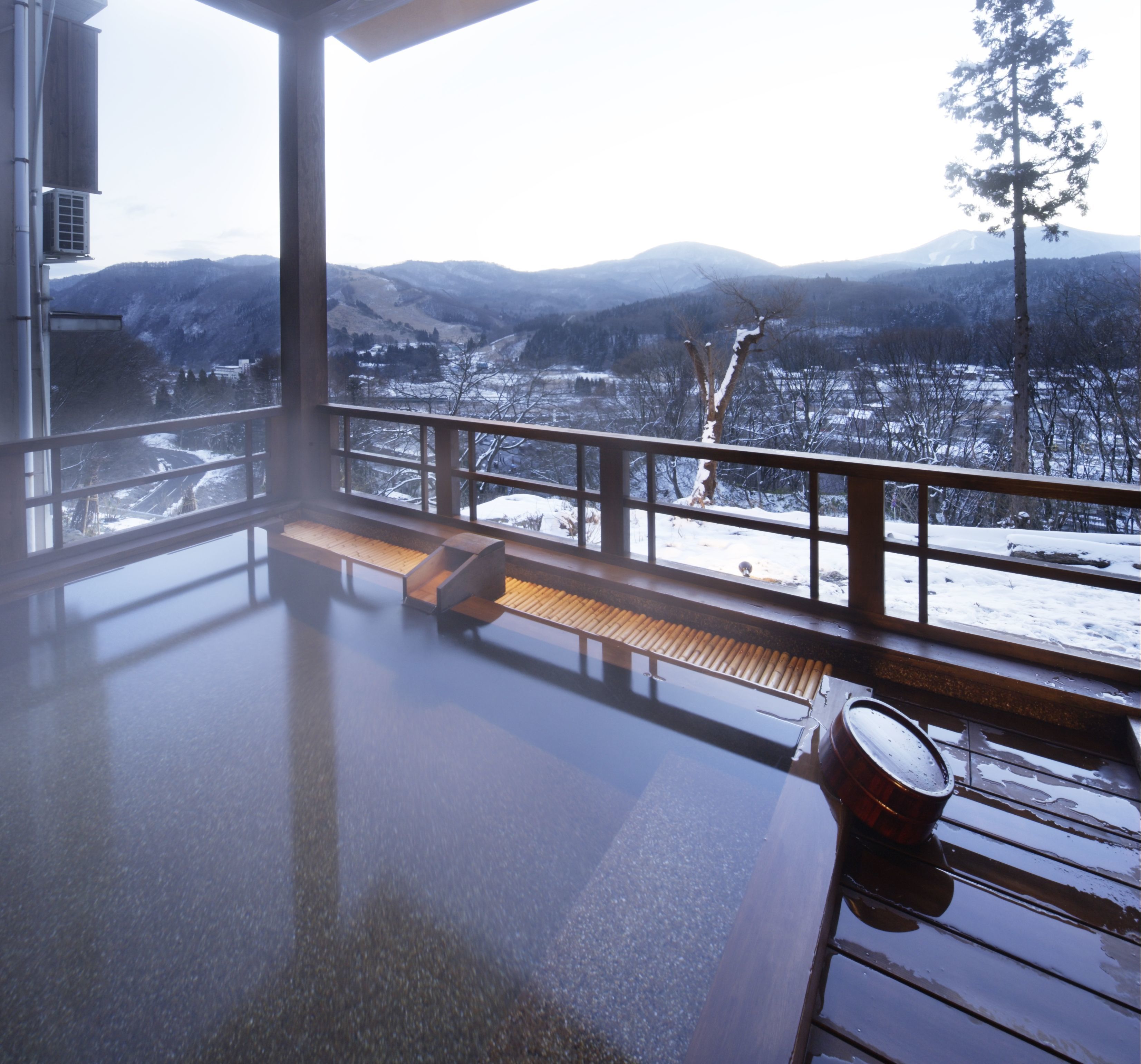 Une chambre avec vue sur des montagnes enneigées et une terrasse en bois.