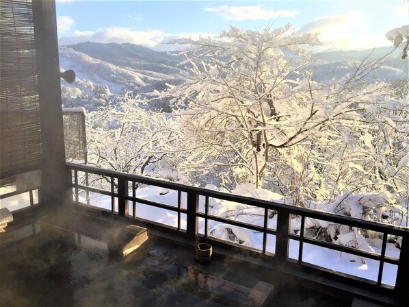 Un balcon offrant une vue sur des arbres et des montagnes enneigés.