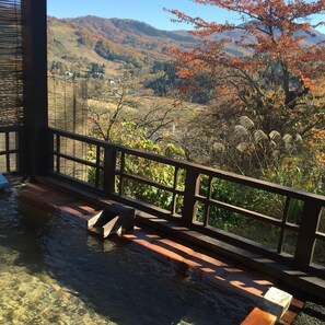 A view from a balcony with a wooden railing overlooking a mountainous landscape with autumn foliage. - Kofukan (Myoko)