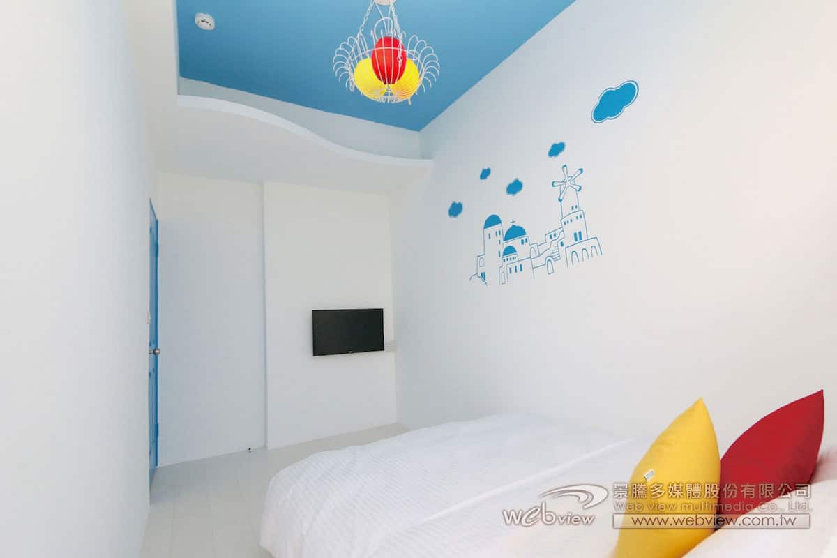Ein Schlafzimmer mit einem Bett, einem an der Wand montierten Fernseher und einer dekorativen Wandsticker.