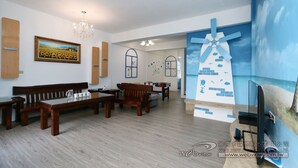 Un salon meublé de meubles en bois, orné d’un tableau de tournesols et d’une fresque représentant un moulin à vent.