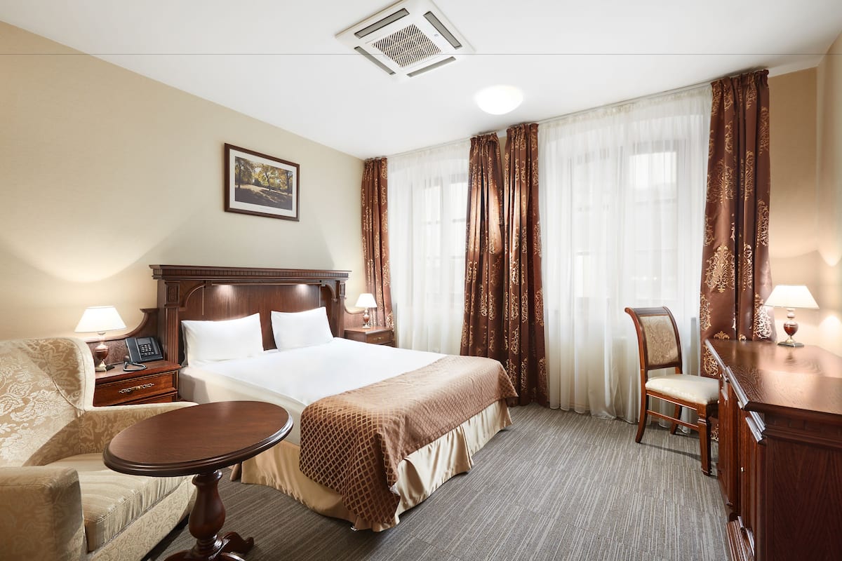 Hotellihuone, jossa on suuri sänky, työpöytä, tuoli ja pieni pöytä.