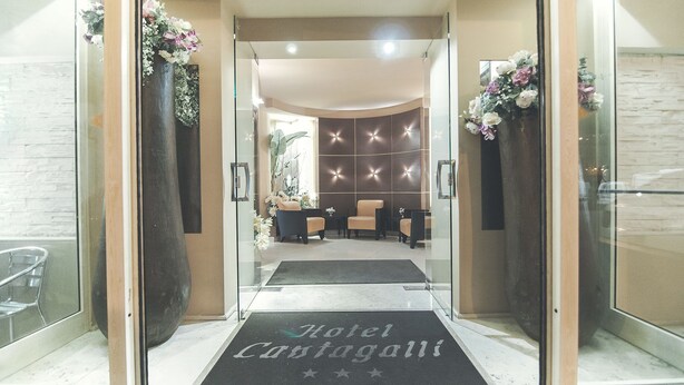 Een hotelentree met een receptiebalie, een zithoek en een decoratieve wand.