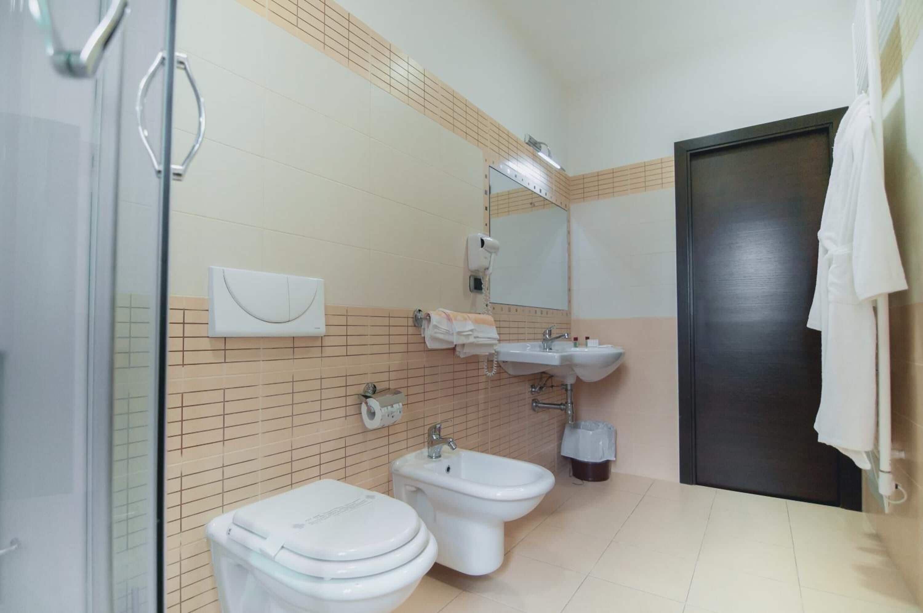 A bathroom with a toilet, bidet, sink, and a mirror.