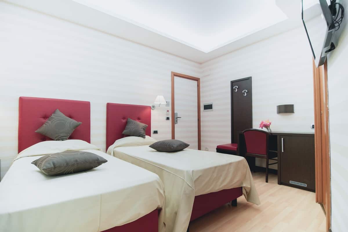 Une chambre d’hôtel avec deux lits, un bureau et une armoire.