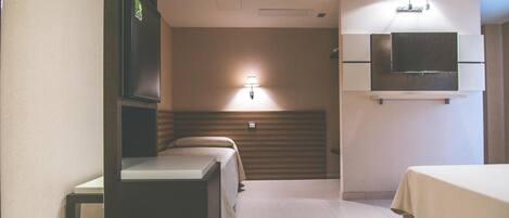 Habitación de hotel con cama, escritorio, silla, televisión montada en la pared y ventana.