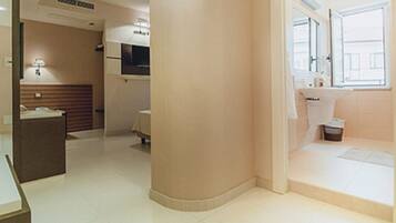 A hotel room with a bed, a bedside table, a window, and a bathroom with a sink and toilet.