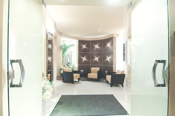 Un vestíbulo moderno con zona de estar, una pared decorativa y entrada por puerta de cristal.