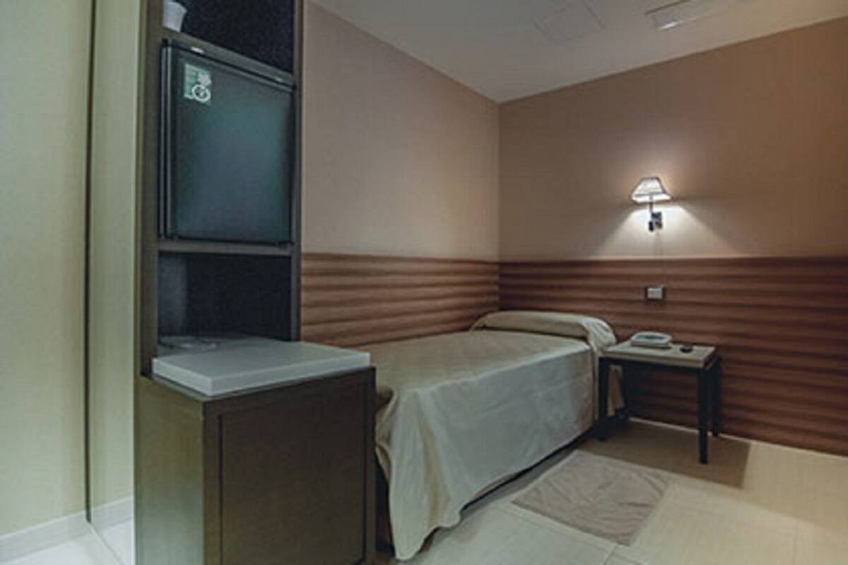 Une chambre d’hôtel équipée d’un lit, d’une table de chevet, d’une lampe et d’un téléviseur.