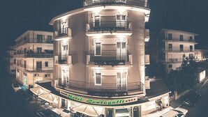 Een hotel met meerdere verdiepingen, balkons, een restaurant op de begane grond en een zichtbare entree.