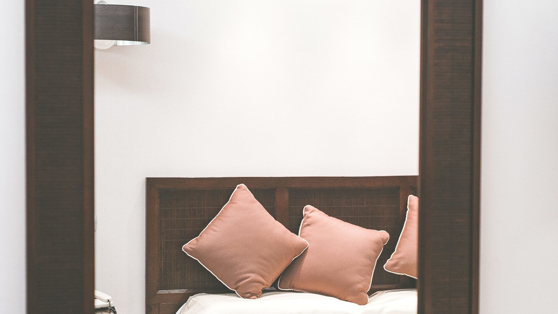 Un dormitorio con cabecera de madera, dos almohadas y una lámpara de noche.
