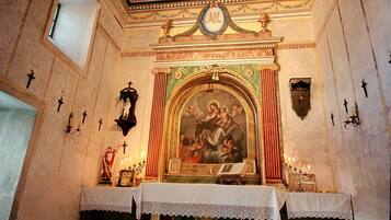 Un interior con un altar religioso, un fresco y un techo ricamente decorado.