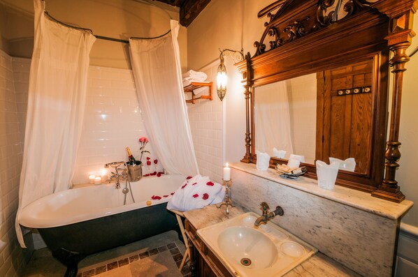 A bathroom with a bathtub, a sink, and a vanity mirror.
