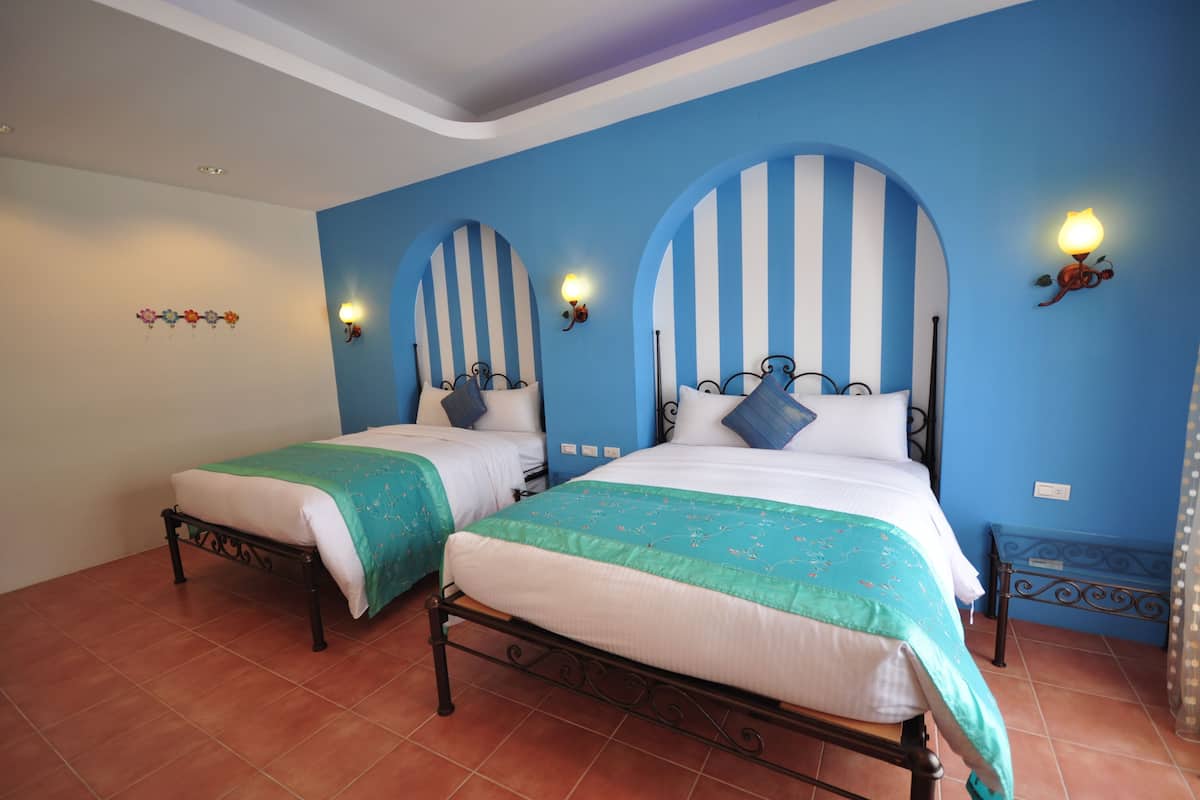 A room with two beds, each with a striped headboard and a bedside lamp.