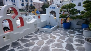 A rooftop terrace with stone flooring, white and red decorative railings, and potted plants. - Greece Style Hotel (Hengchun)