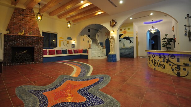 A spacious lobby with a tiled floor, a brick fireplace, and a colorful mosaic rug. - Greece Style Hotel (Hengchun)