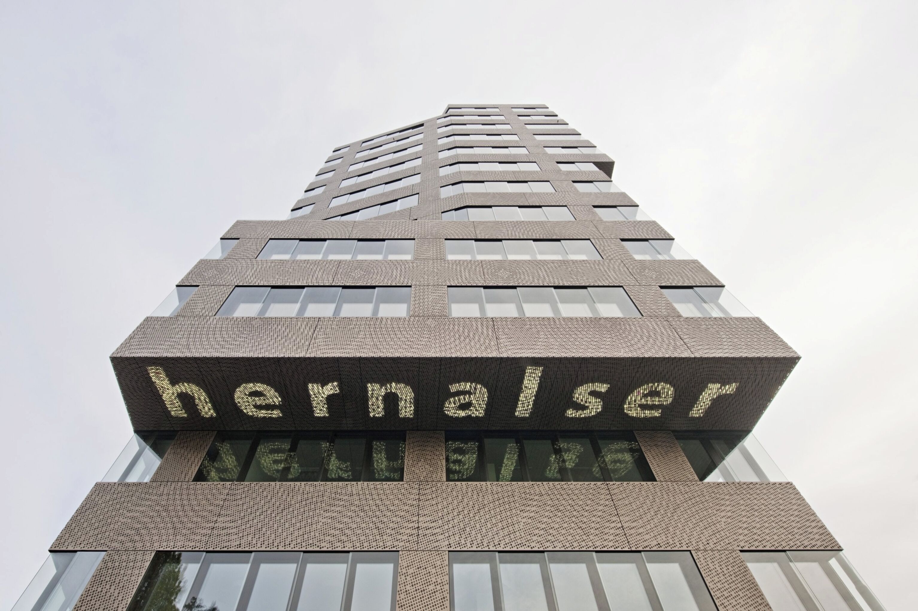 A tall building with a modern design, featuring a prominent sign with the word "hernalser" on its facade.