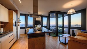 A modern kitchen with a central island, dining area with a sofa, and large windows offering city views. - Skyflats Vienna - Rooftop Apartments (Vienna)