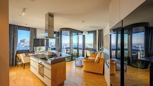 A modern apartment with a kitchen, dining area, and living room, featuring large windows and a city view. - Skyflats Vienna - Rooftop Apartments (Vienna)